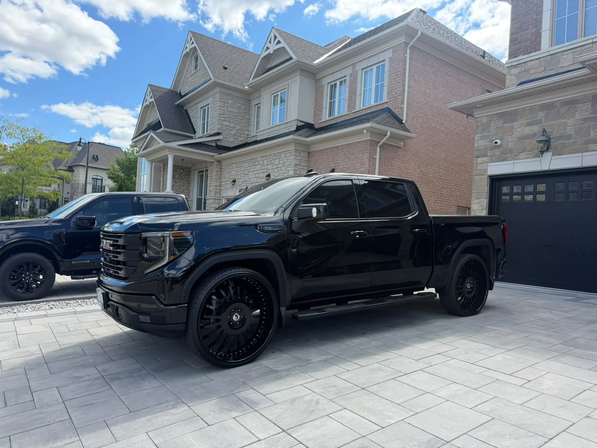 Blacked-out GMC Sierra on custom wheels with tinted windows, detailed by Bachelor Tint